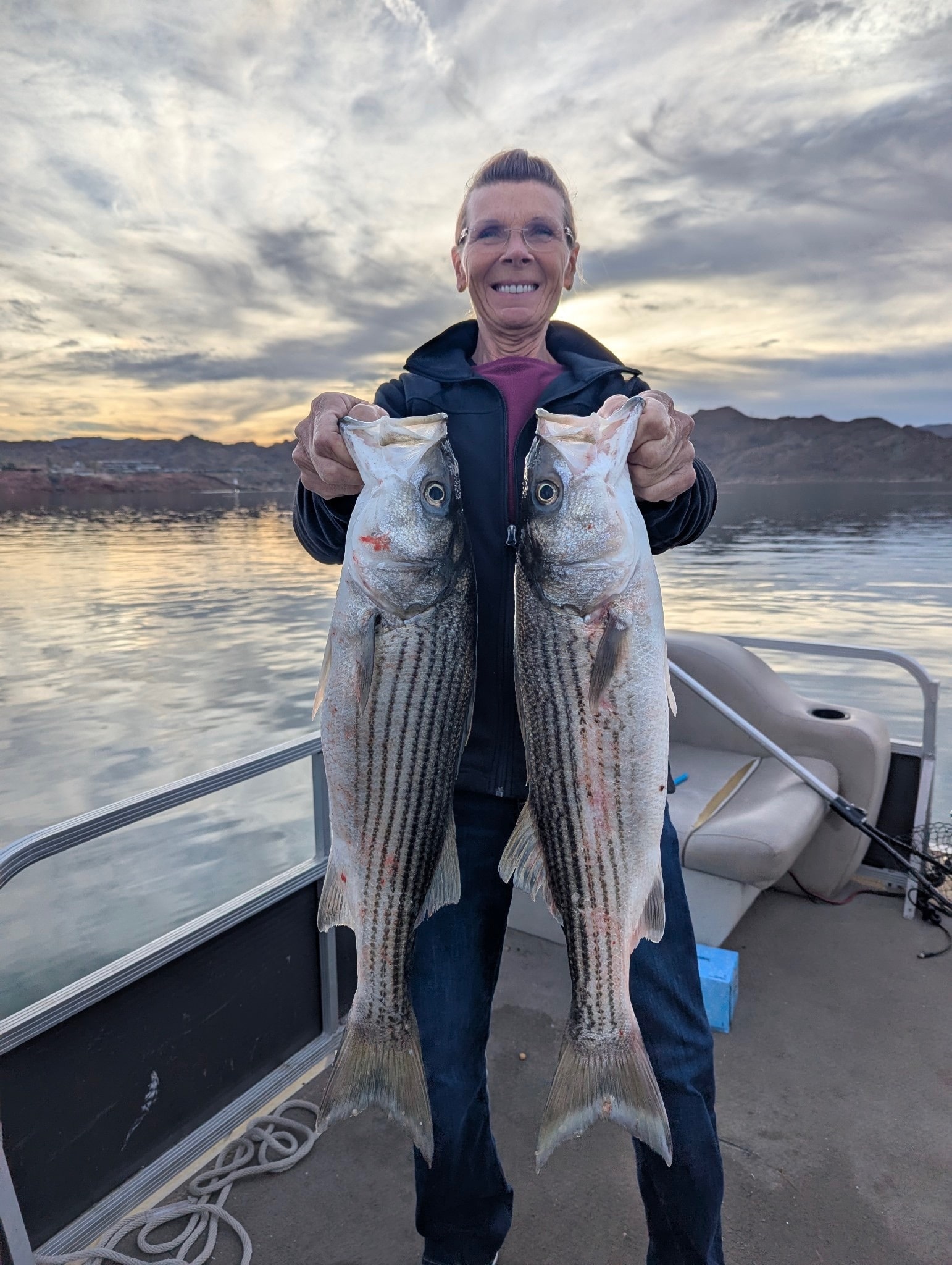 Angler smiling and holding several striped bass